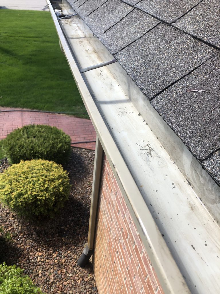 Clean rain gutters and downspout protecting a Pewaukee, WI home's foundation.